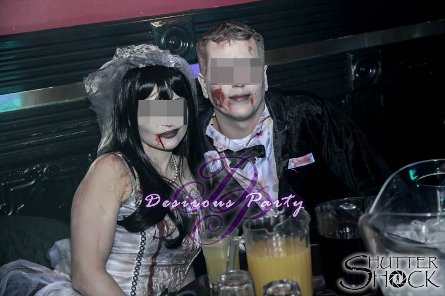 Sexy zombie couple having bottle service at the halloween erotica ball. 